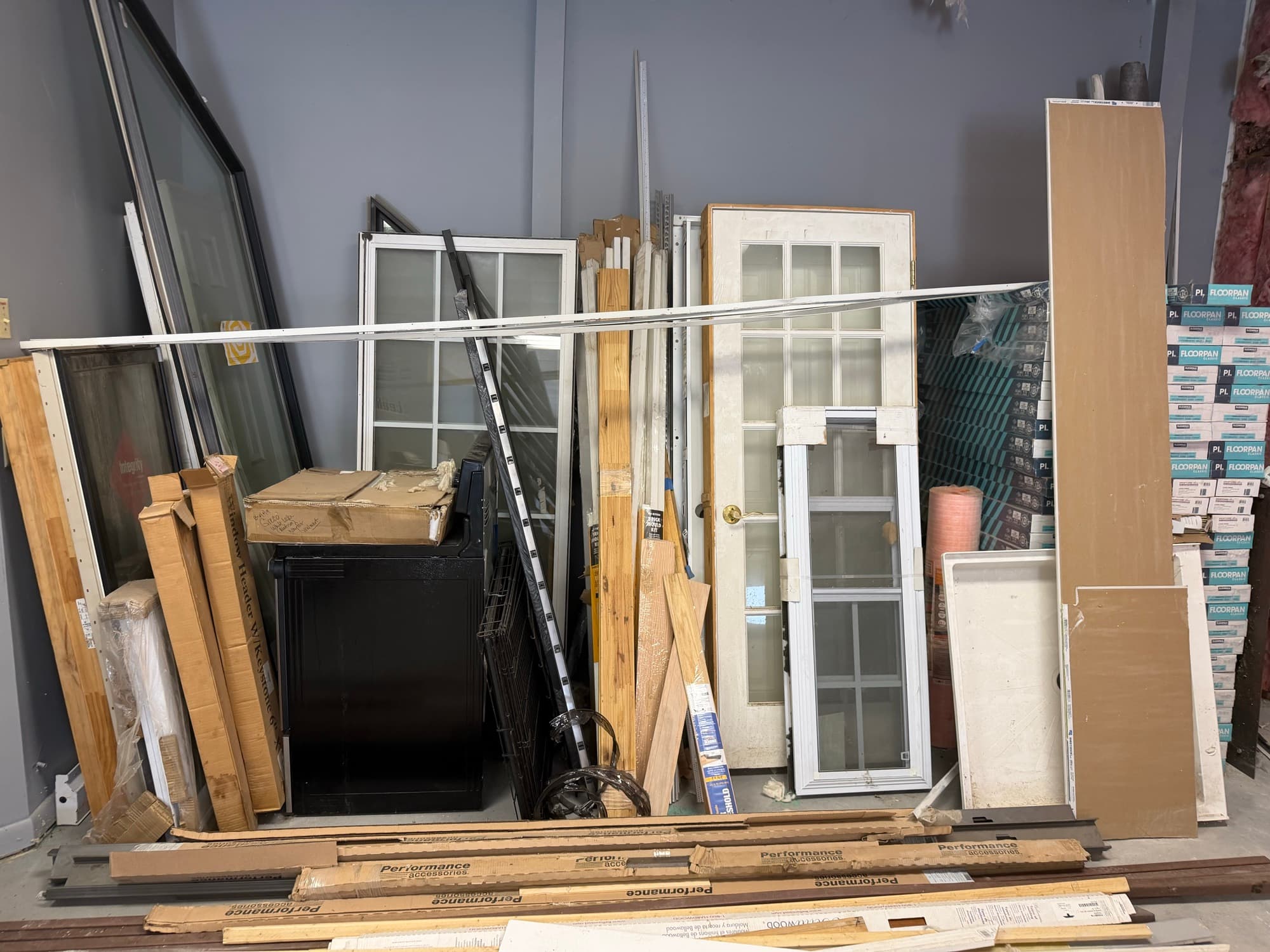Doors, windows and building materials stacked against the warehouse wall